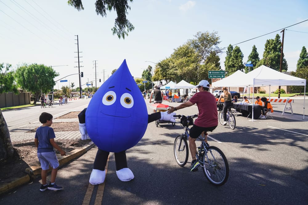Long Beach Utilities droplet mascot giving cyclist a high five